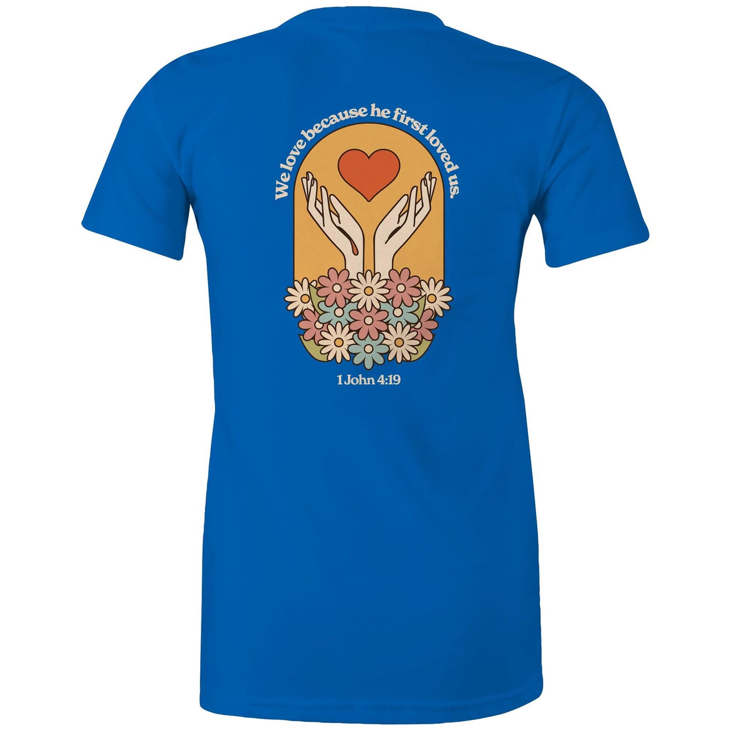 Christian t-shirt with bold faith-based design on the back featuring a red heart, outstretched hands, and colorful flowers. Includes the Bible verse “We love because he first loved us – 1 John 4:19.” Designed by Lighthouse Christian Clothing to inspire love and faith.