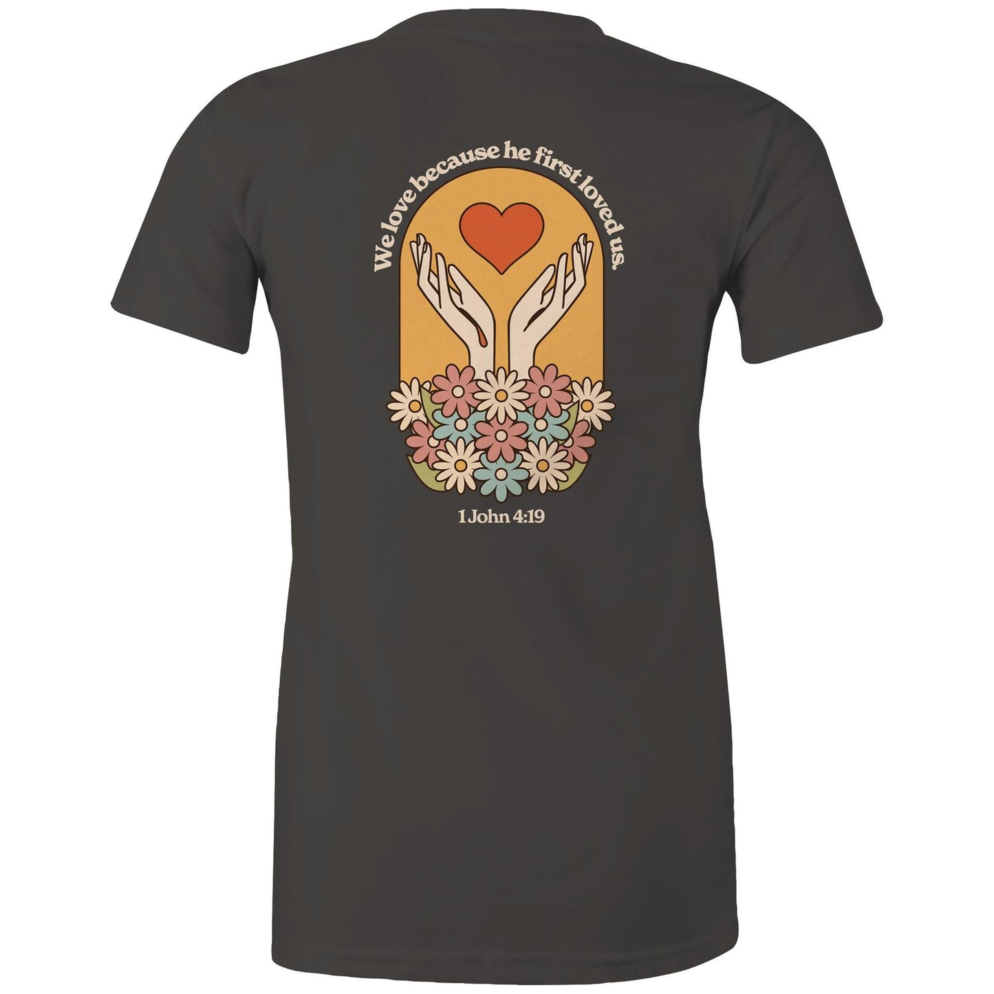 Christian t-shirt with bold faith-based design on the back featuring a red heart, outstretched hands, and colorful flowers. Includes the Bible verse “We love because he first loved us – 1 John 4:19.” Designed by Lighthouse Christian Clothing to inspire love and faith.
