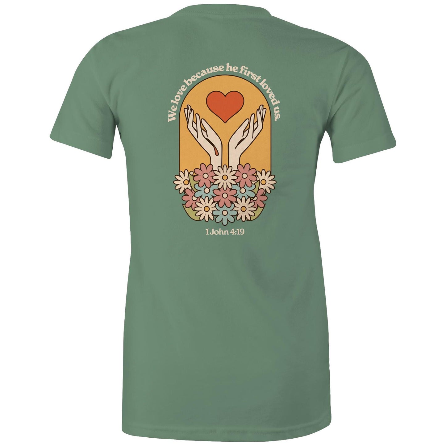 Christian t-shirt with bold faith-based design on the back featuring a red heart, outstretched hands, and colorful flowers. Includes the Bible verse “We love because he first loved us – 1 John 4:19.” Designed by Lighthouse Christian Clothing to inspire love and faith.