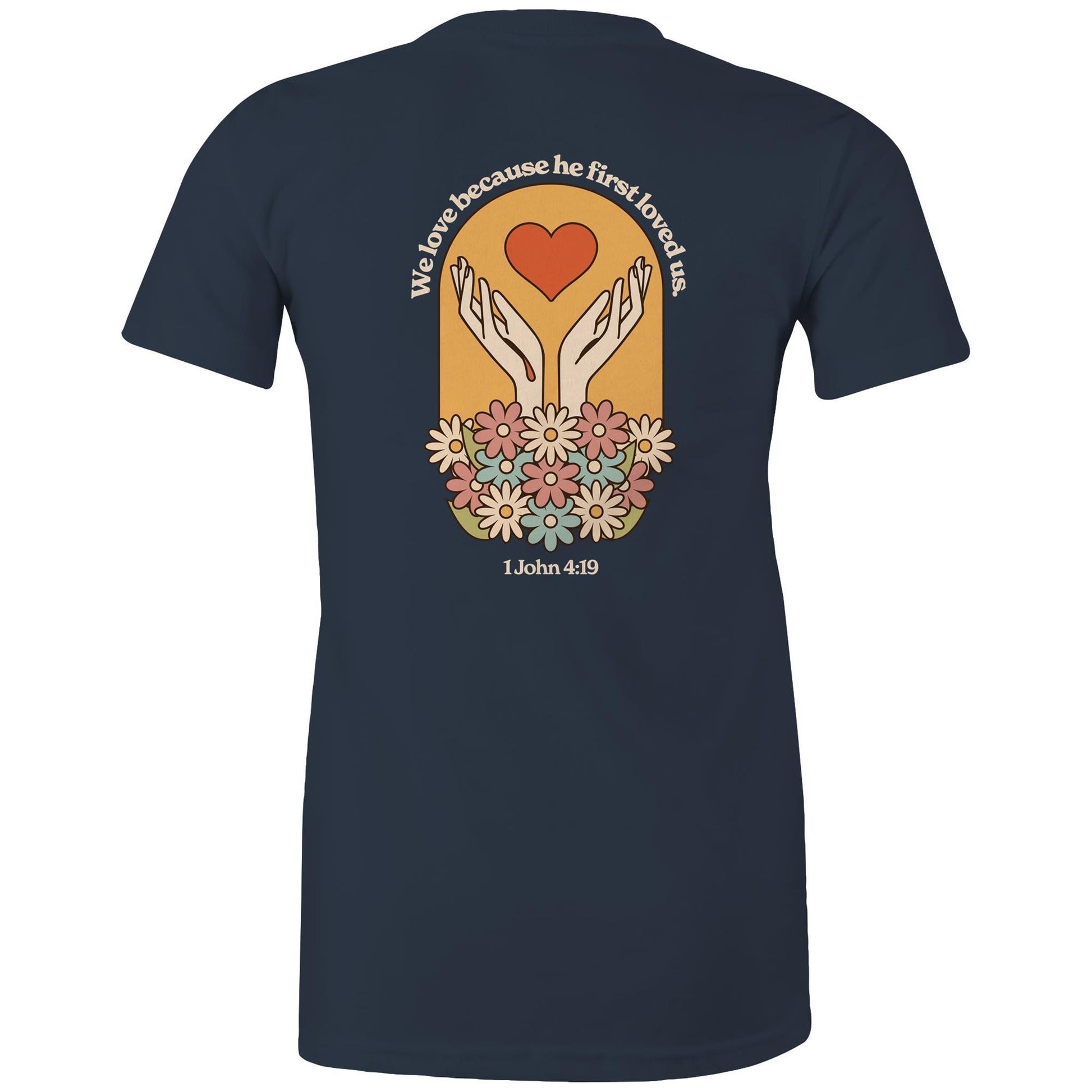 Christian t-shirt with bold faith-based design on the back featuring a red heart, outstretched hands, and colorful flowers. Includes the Bible verse “We love because he first loved us – 1 John 4:19.” Designed by Lighthouse Christian Clothing to inspire love and faith.
